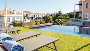 A poolside area with lounge chairs and towels, a clear blue pool, and a view of surrounding buildings. - Vale Lobo  Golf & Beach with Private Pool I (Vale do Lobo)