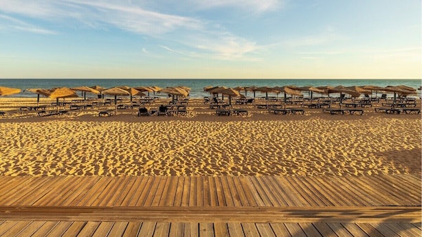A beach with wooden deck chairs and umbrellas, a sandy beach, and the ocean in the background. - Vale Lobo  Golf & Beach with Private Pool I (Vale do Lobo)