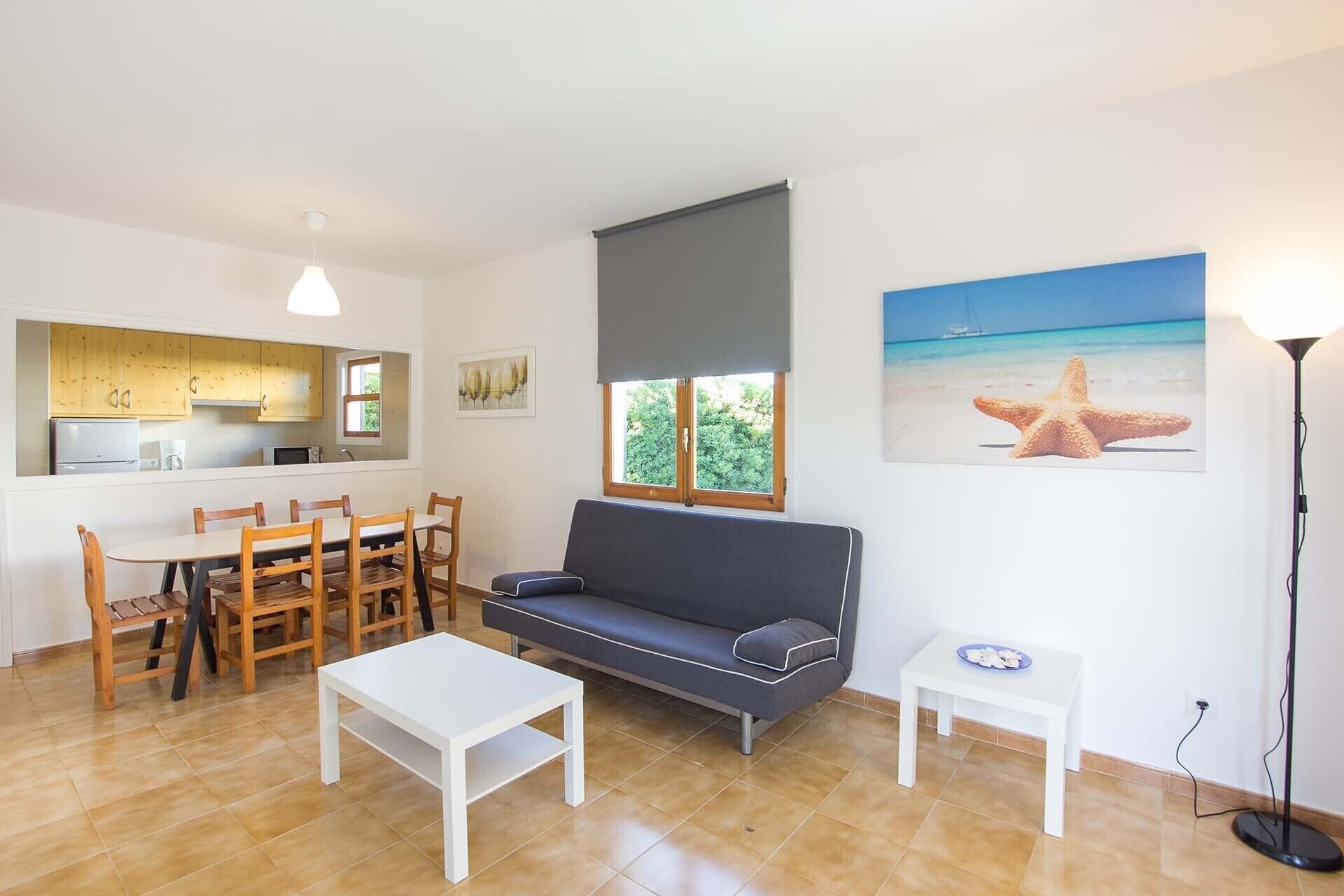 Una sala de estar con sofá, mesa de comedor, sillas, máquina de café y zona de cocina.