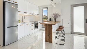 Una cocina moderna con armarios blancos, electrodomésticos de acero inoxidable y una isla de madera con taburetes de bar.