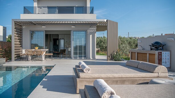 Una casa moderna con piscina, mobiliario de exterior y zona de barbacoa.