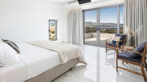Un dormitorio moderno con cama, una silla, televisión y vistas al exterior.