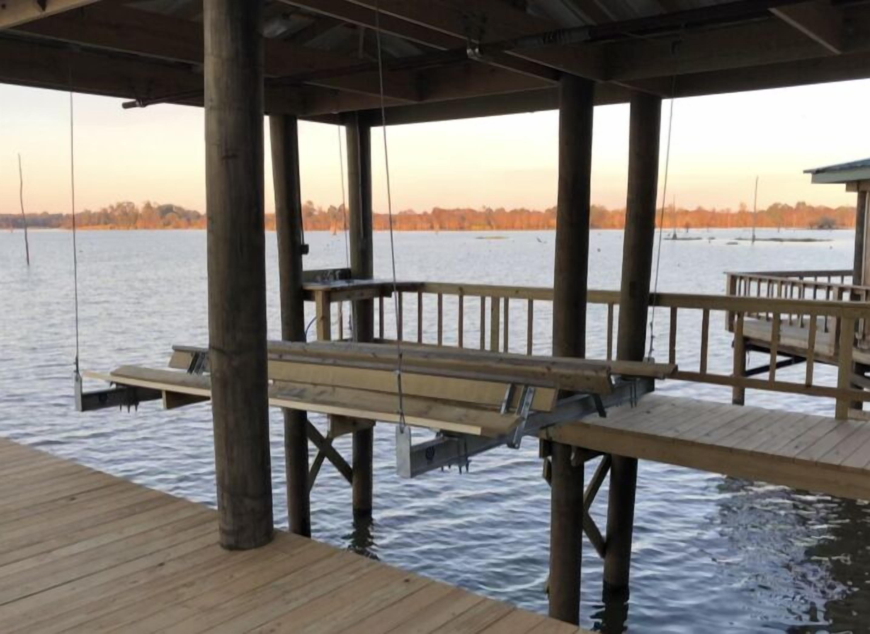 Una banchina in legno che si estende sull'acqua, con panchine e tavoli, sostenuta da pilastri di legno.