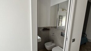 Un bagno moderno con bidet, WC e uno specchio.