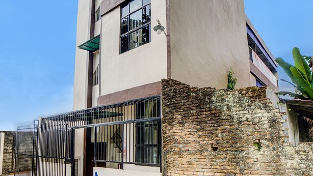 Un edificio con pared de ladrillo, portón metálico y dispensador de agua en el exterior.