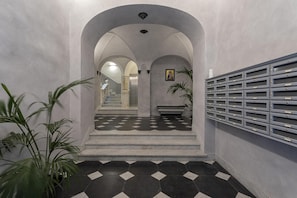 Stunning hallway with a checkered floor, arched doorways, and vaulted ceiling, featuring potted plants and a storage cabinet.