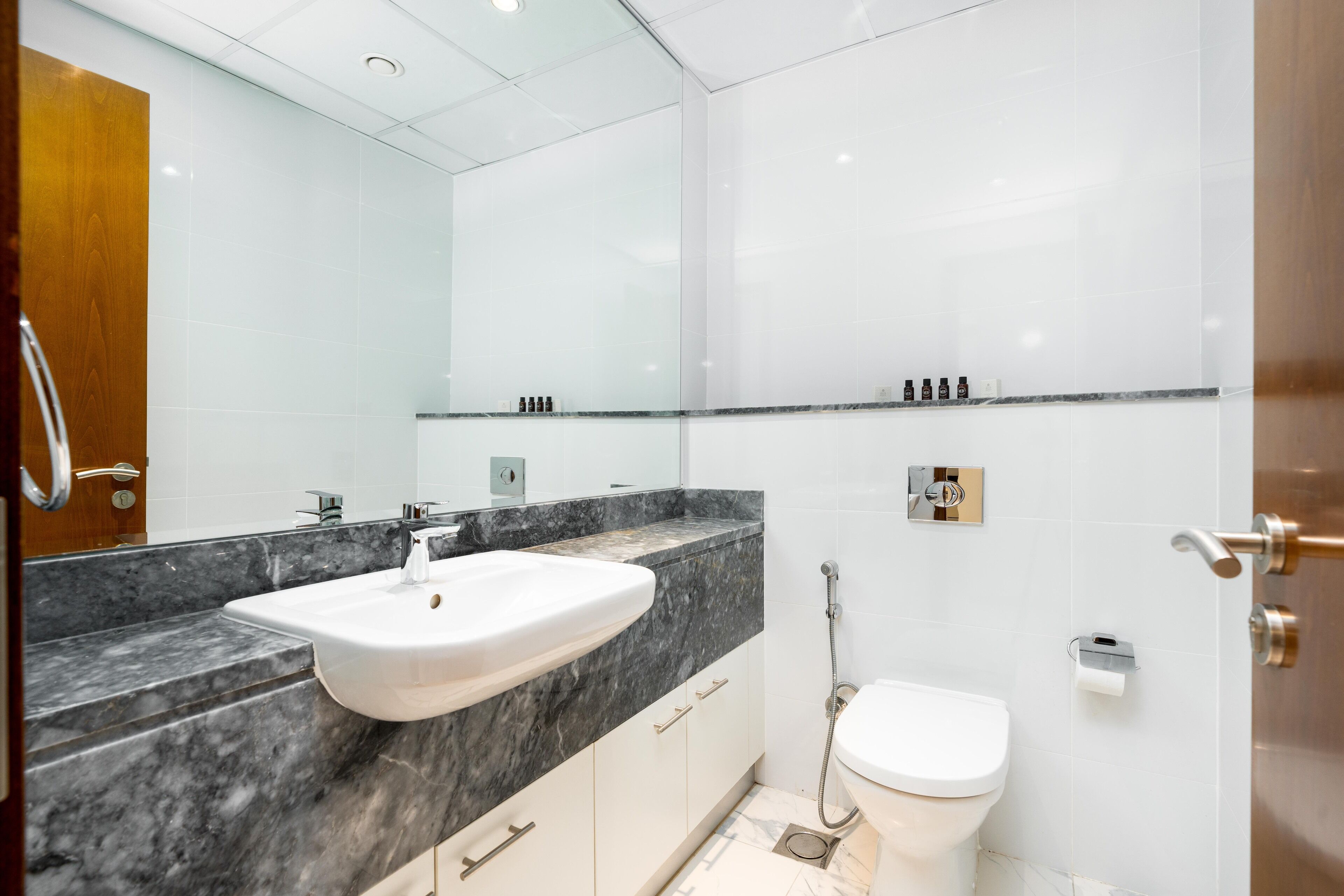 A modern bathroom with a marble sink, a toilet, and a glass shower enclosure.