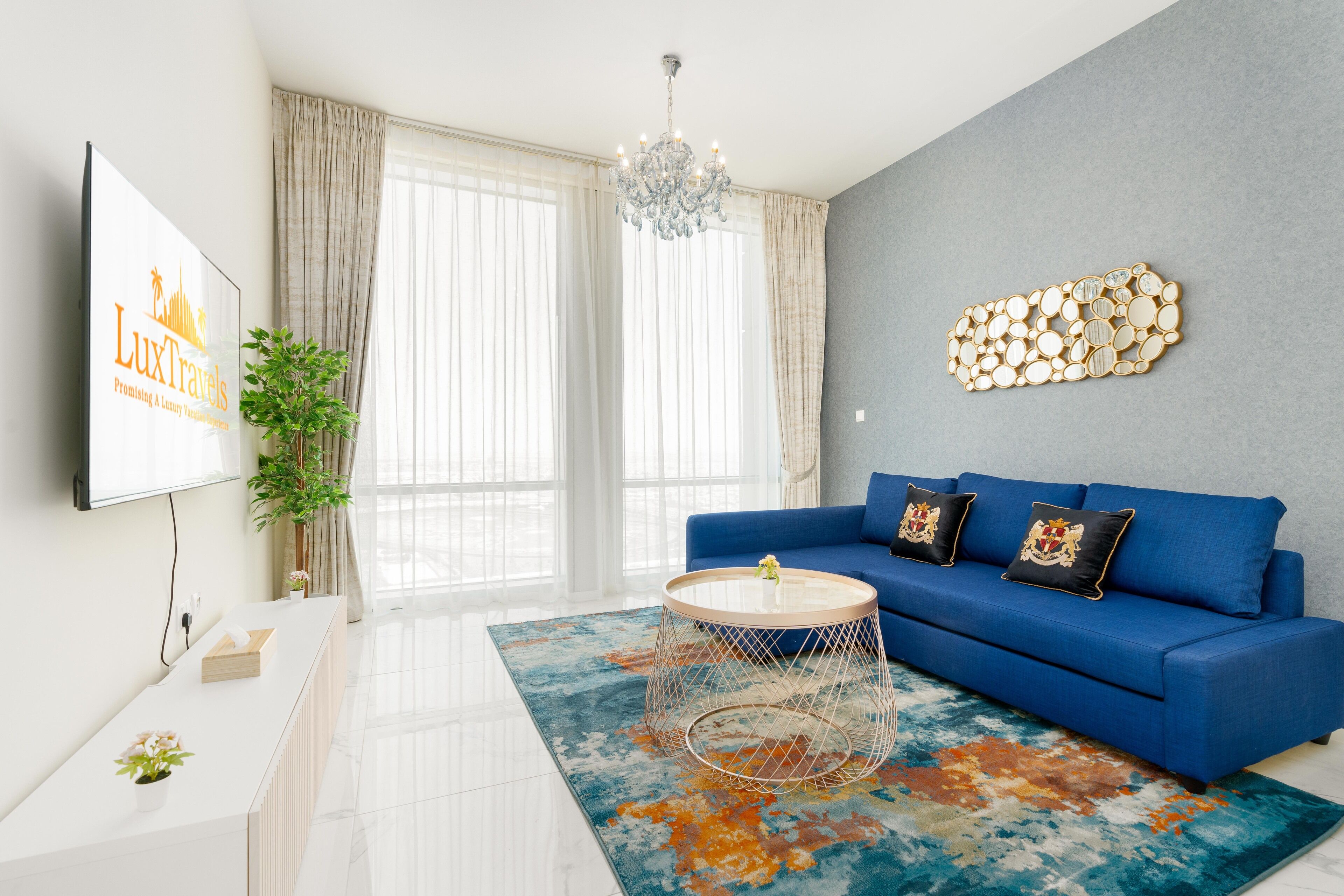 Ein modernes Wohnzimmer mit einem blauen Sofa, einem runden Couchtisch und einem großen Fenster mit Vorhängen.