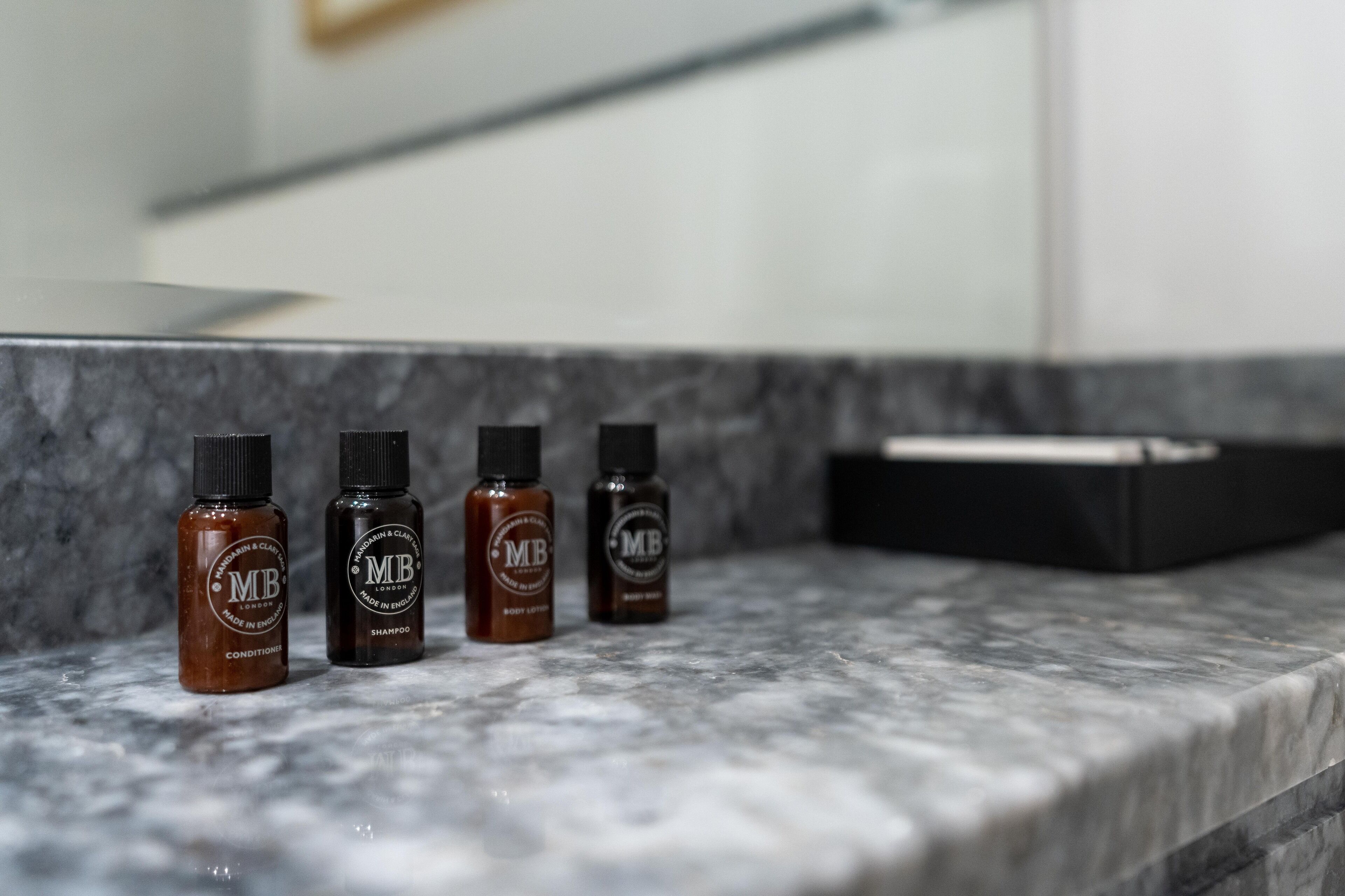 Three bottles of body lotion on a marble countertop.