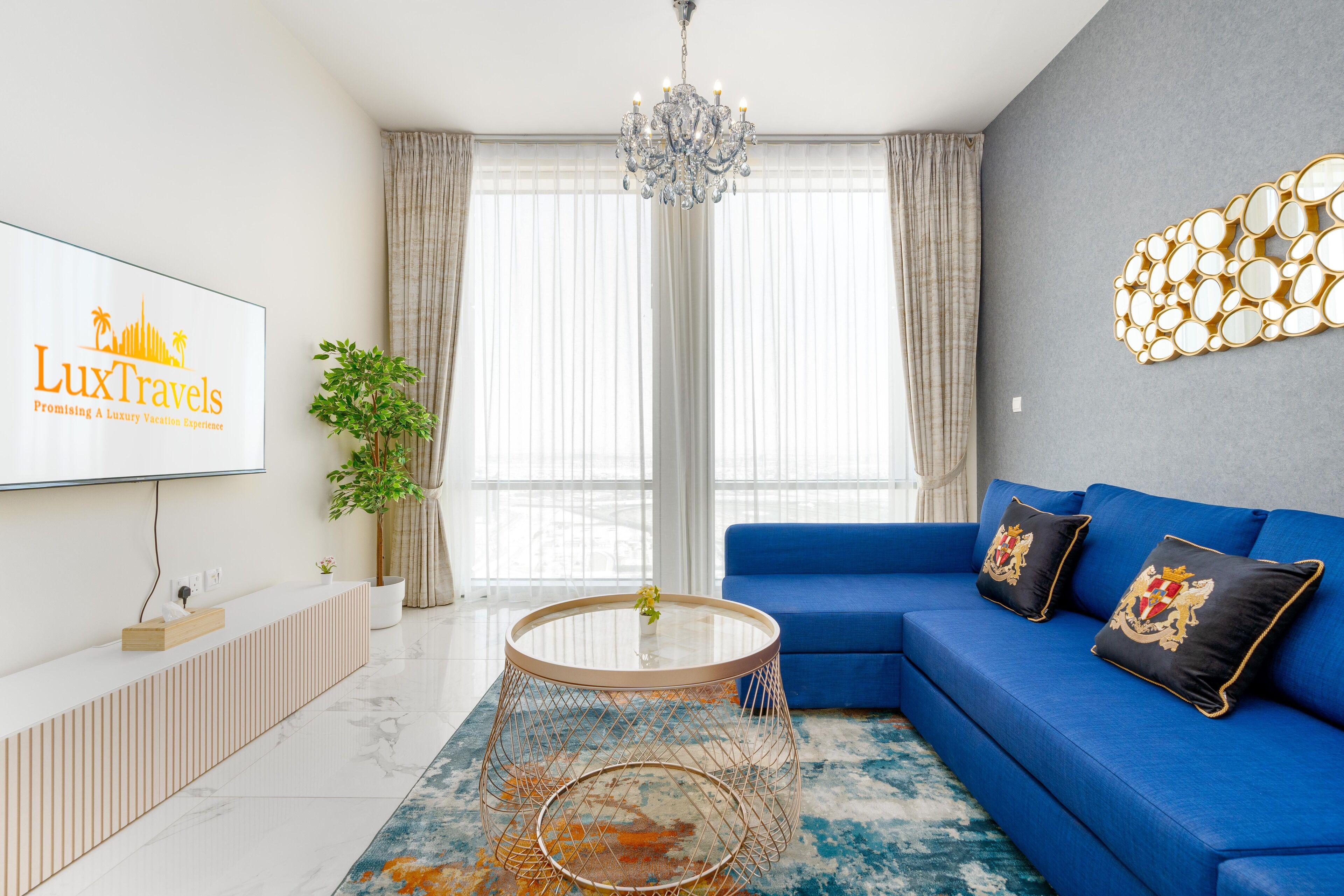 Una sala moderna con un sofá azul, una mesa de centro redonda y una araña.
