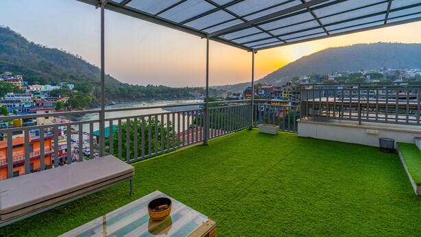 A balcony with artificial grass, a bench, and a table with a bowl. - Madpackers Rishikesh (Yamkeshwar)