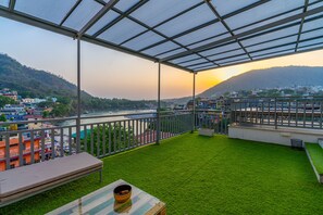 A balcony with artificial grass, a bench, and a table with a bowl. - Madpackers Rishikesh (Yamkeshwar)