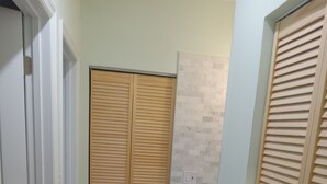 Een gang met een houten kast, een betegelde vloer en een lichtgekleurde muur.