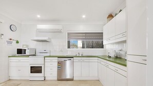 Une cuisine moderne avec des meubles blancs, un lave-vaisselle, un four à micro-ondes et une fenêtre donnant sur un beau paysage.