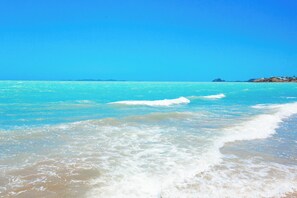 A beach with clear turquoise water and a sandy shore. - Absolute beachfront - and your own private swimming pool!? (Yeppoon)