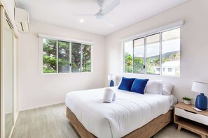 A bedroom with a bed, a nightstand, a lamp, and a ceiling fan. - Absolute beachfront - and your own private swimming pool!? (Yeppoon)