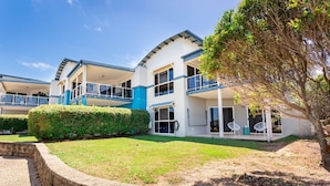 A modern two-story building with balconies, a well-maintained lawn, and a stone retaining wall. - Catalina Island Views - What an understatement! (Yeppoon)