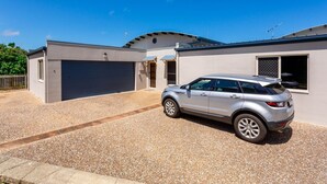 A modern two-story house with a garage, a gravel driveway, and a silver SUV parked in front. - Catalina Island Views - What an understatement! (Yeppoon)
