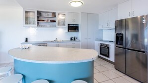 A modern kitchen with a central island, white cabinetry, stainless steel appliances, and a built-in microwave. - Catalina Island Views - What an understatement! (Yeppoon)