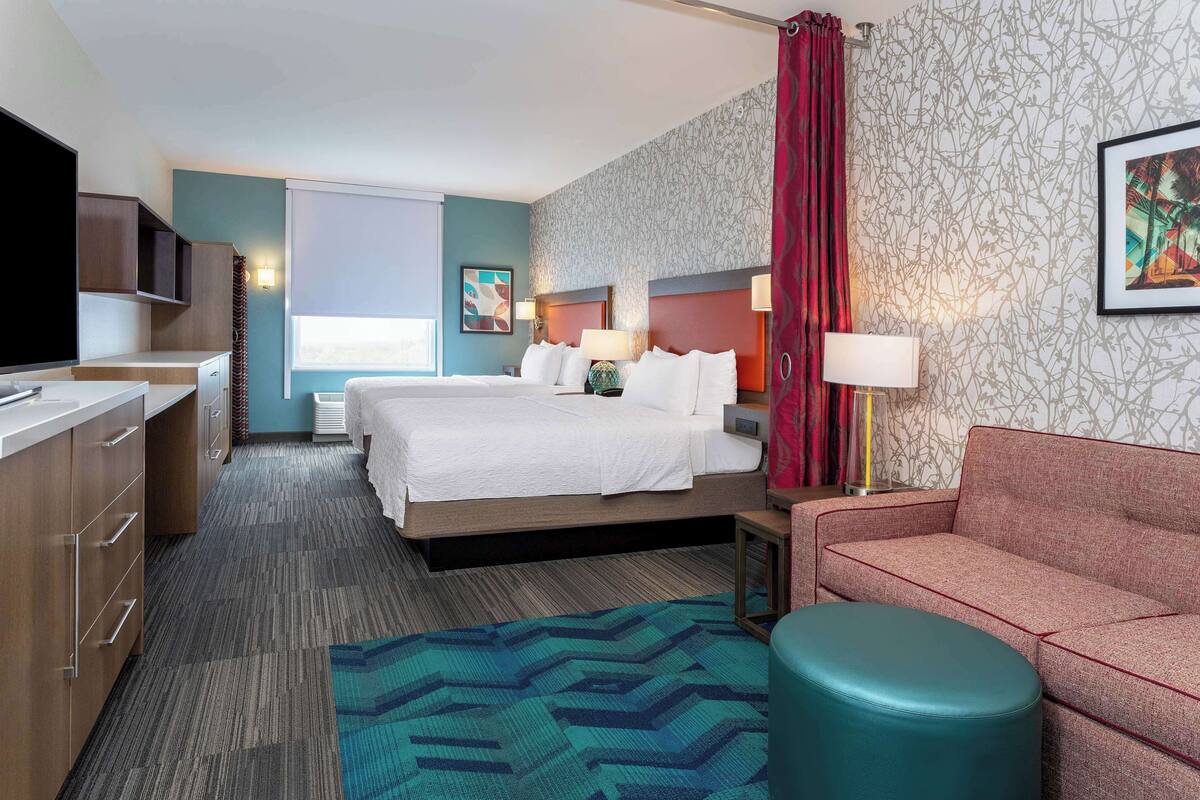 A hotel room with a bed, a sofa, a TV, and a desk.