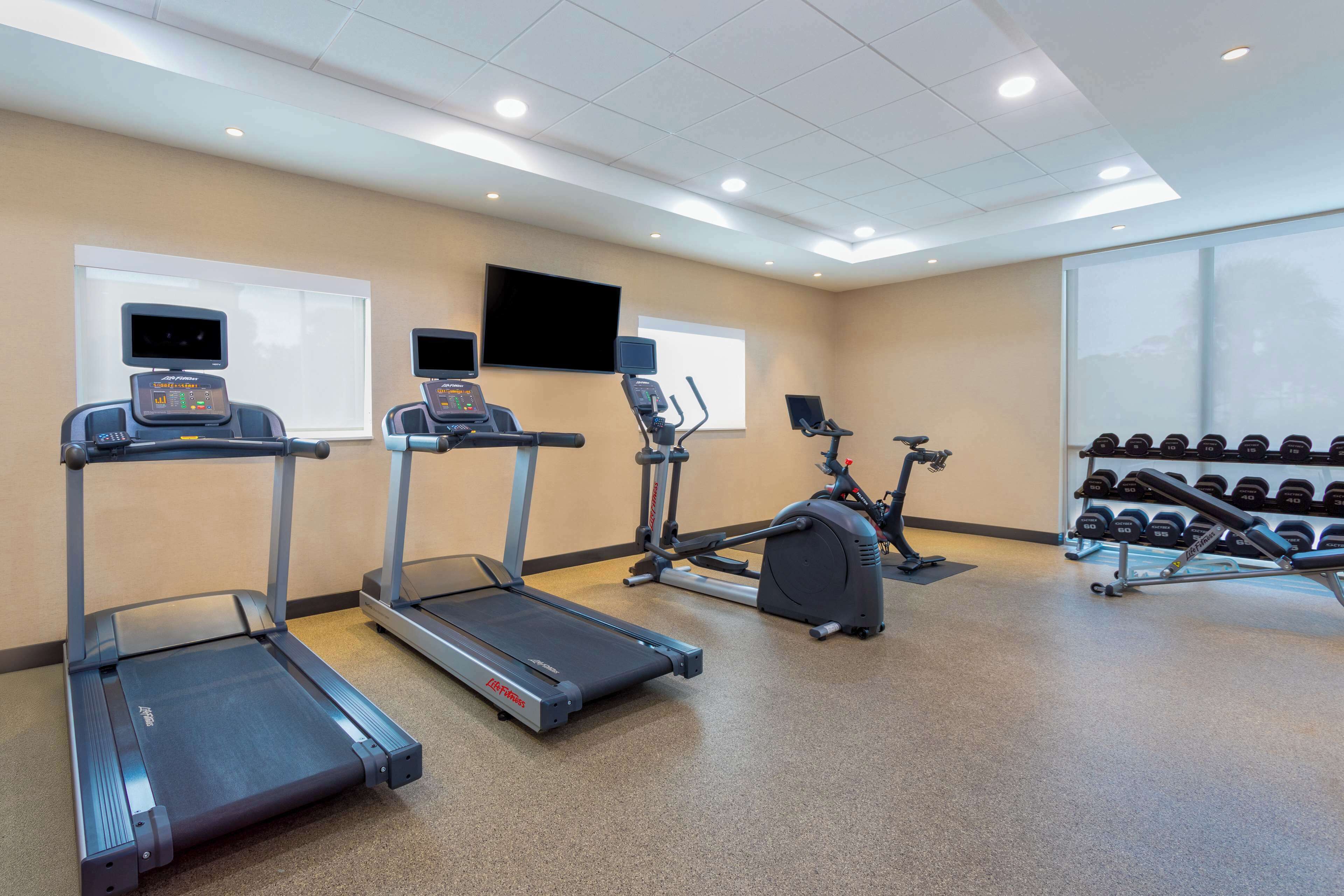 A gym with treadmills, an elliptical, and a weight bench.