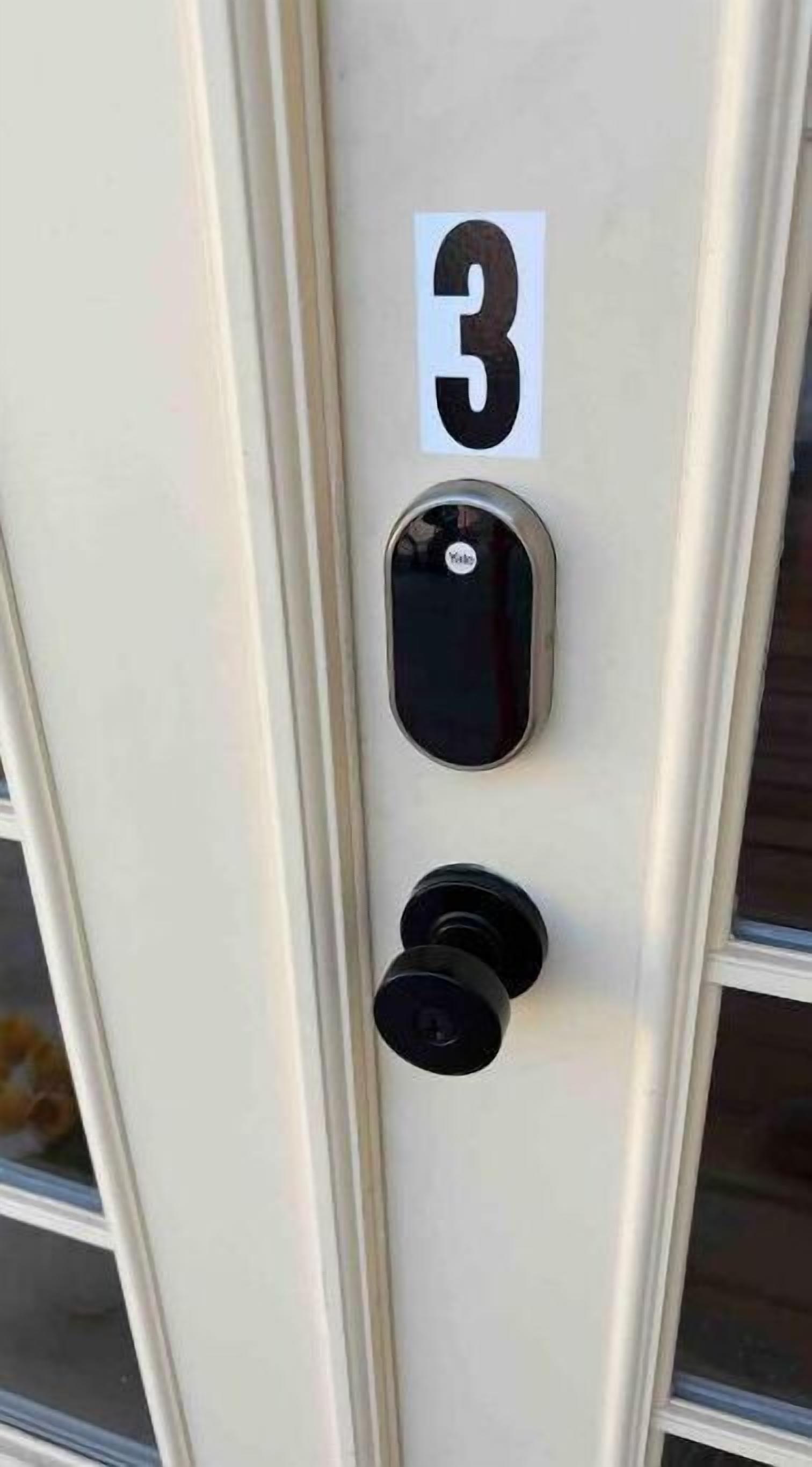 Una puerta con una placa numerada '3', un moderno sistema de cierre electrónico y una cerradura tradicional.