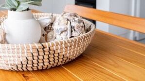 Eine Küche mit Holzschränken, einer weißen Arbeitsplatte und einem Blumentopf auf einem Tisch.