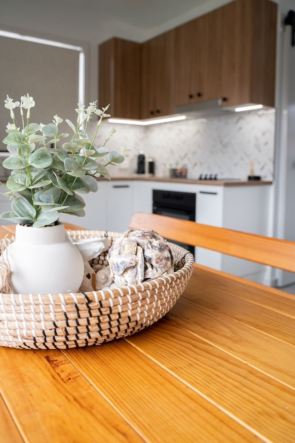 Una cocina con armarios de madera, encimera blanca y una planta en maceta sobre una mesa.