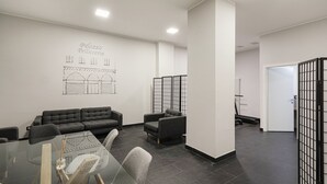 Ein modernes Interieur mit einer Couch, Stühlen, einem Glastisch und einer Wand mit architektonischen Zeichnungen.