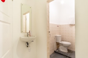 Un baño con lavamanos, espejo, inodoro y paredes de azulejos.
