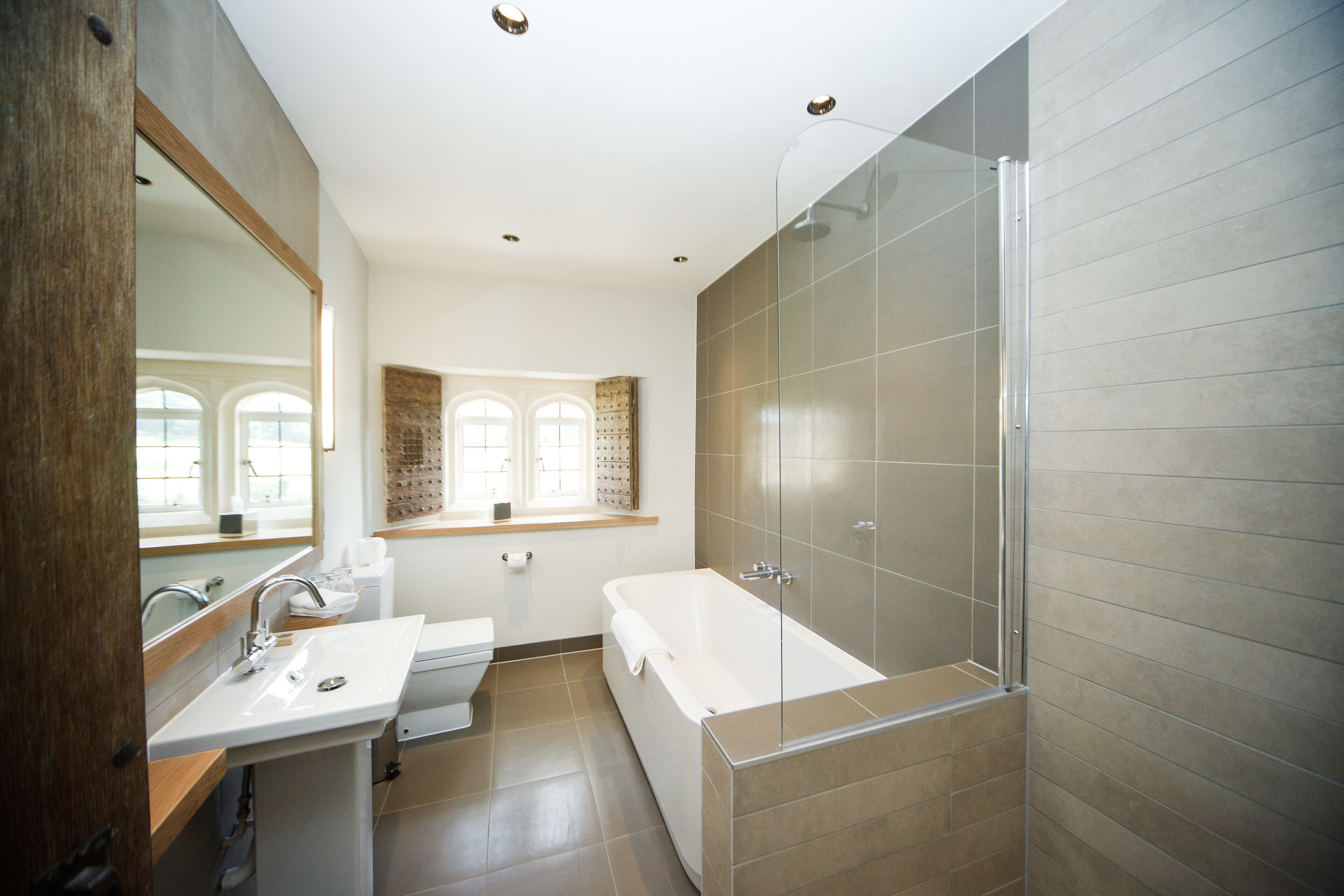 A modern bathroom with a large mirror, a sink, a toilet, and a glass-enclosed shower.