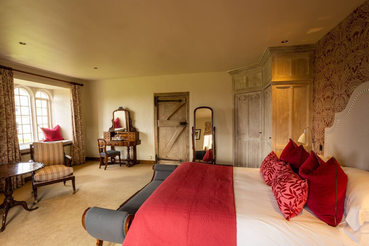 A bedroom with a bed, a desk, a chair, a window, and a wardrobe.