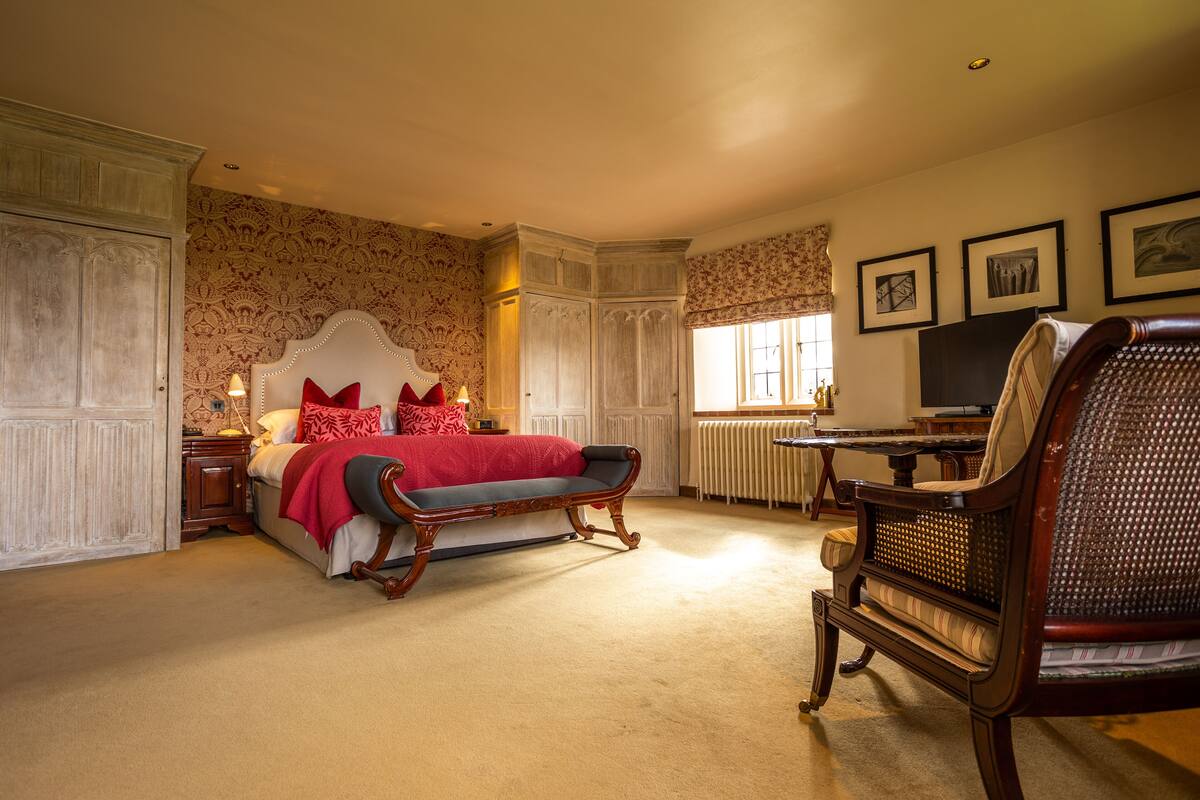 A bedroom with a large bed, a wooden chair, a desk, and a radiator.