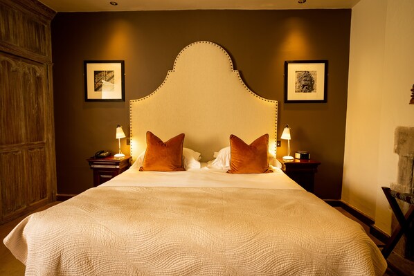A large bed with a high, ornate headboard, two bedside tables with lamps, and framed pictures on the walls. - Maidens Tower B&B (Maidstone)