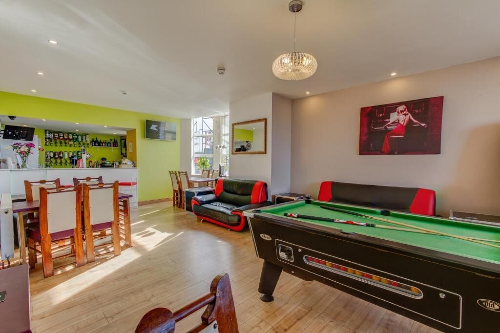 A pool table in a room with a bar area and seating.