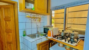 A kitchen with wooden cabinets, a microwave, a stove, and a window. - 1 Bed Studio Sleeps 2 - Wifi, Balcony, Parking (Douala)