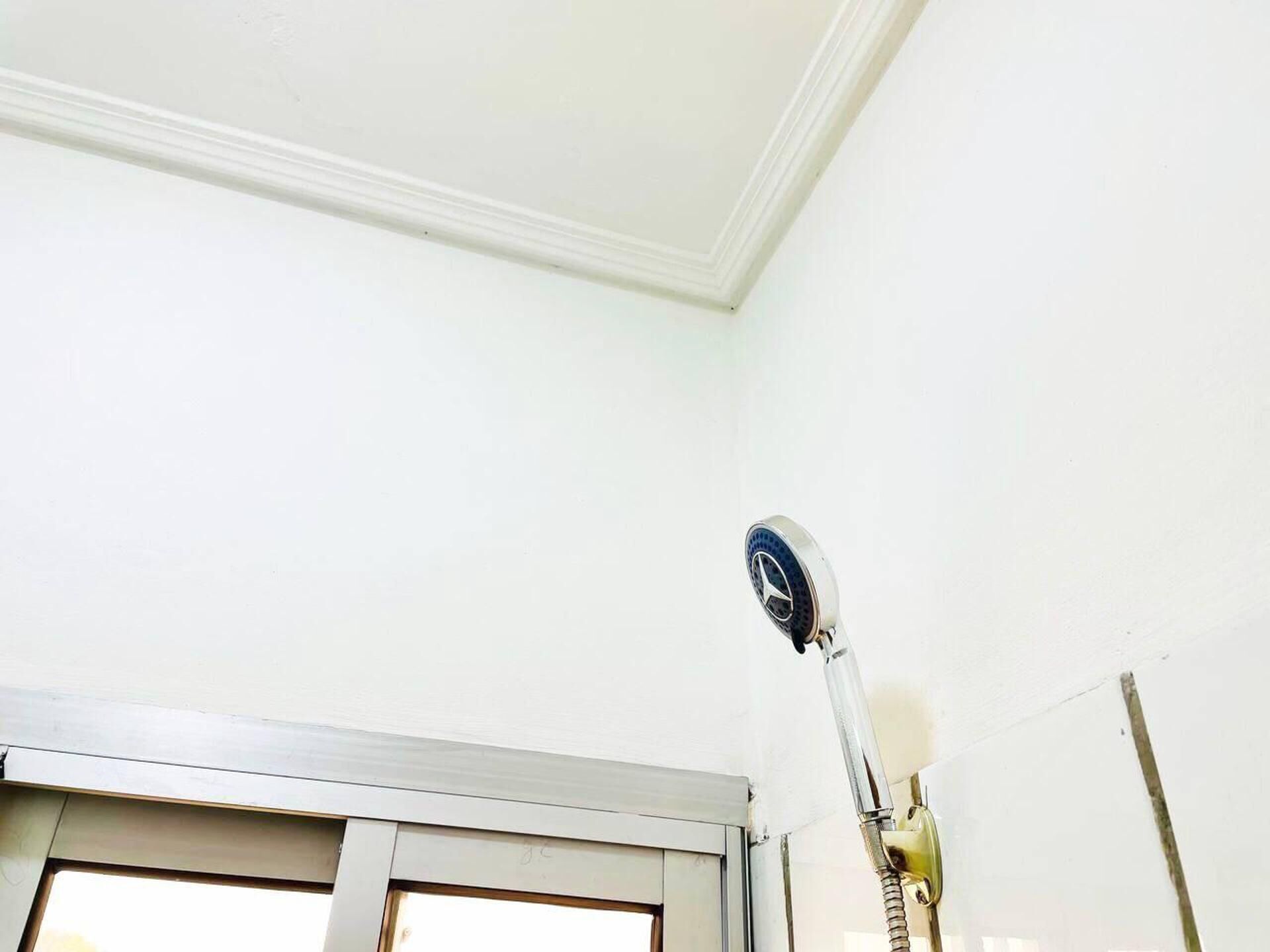 A room with a white ceiling, a door, and a wall-mounted light fixture.