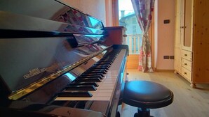 Un piano en una habitación con suelo de madera, un mueble de madera y una ventana con cortinas.