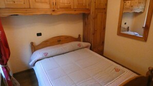 Un dormitorio con estructura de cama de madera, colcha acolchada y armarios de madera sobre la cama.