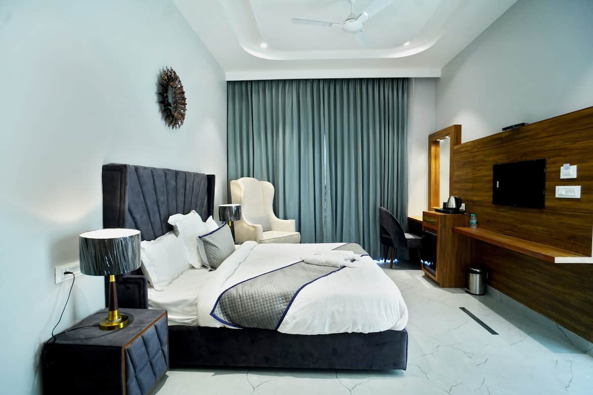Una habitación de hotel moderna con una cama grande, un escritorio, una silla, un televisor y un ventilador de techo.