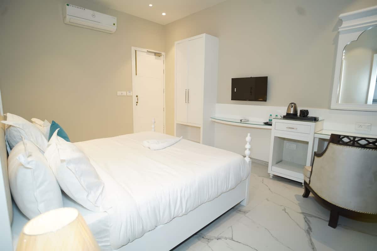 Una habitación de hotel con cama, escritorio, silla, armario y televisor.