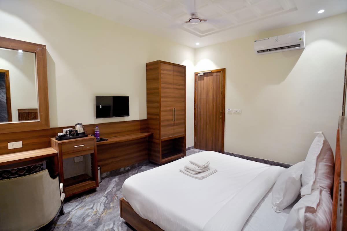 Una habitación de hotel con cama, escritorio, silla, televisor y armario.