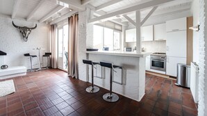 A modern kitchen with white cabinetry, a stainless steel stove, and a small island with bar stools.
