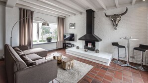 A modern living room with a sofa, a TV, a fireplace, and a bull skull decoration.