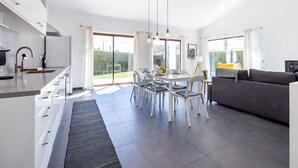 Cozinha moderna com área de refeições, sofá e uma grande porta de vidro deslizante para o exterior.