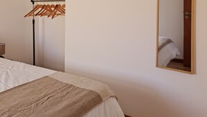 Ein Schlafzimmer mit einem Bett, einem Kleiderständer und einem Spiegel an der Wand.