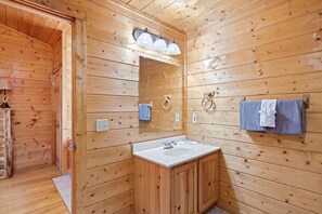 A wooden cabin bathroom with a sink, mirror, and towel rack.