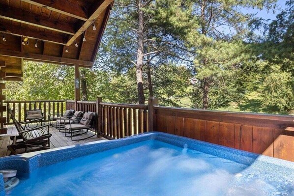 A hot tub on a wooden deck with a view of trees.