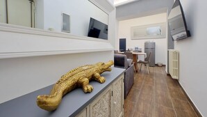 Ein modernes Interieur mit einer großen, goldenen Krokodilsstatue auf einer Theke, einem Essbereich mit Fernseher und einer Küche mit einem großen Spiegel.
