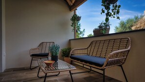 Un balcon agrémenté de meubles en osier, notamment d’un canapé et de fauteuils, ainsi que de plantes en pot.